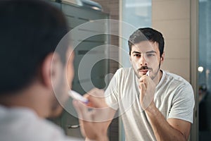 Hispanic Man Brushing Teeth In Bathroom At Morning