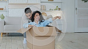 Hispanic man caring loving husband boyfriend pushing large cardboard box with beloved wife curly-haired beautiful woman