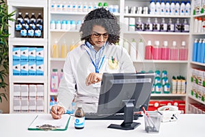 Hispanic man with curly hair working at pharmacy drugstore checking the time on wrist watch, relaxed and confident