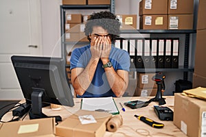 Hispanic man with curly hair working at small business ecommerce rubbing eyes for fatigue and headache, sleepy and tired
