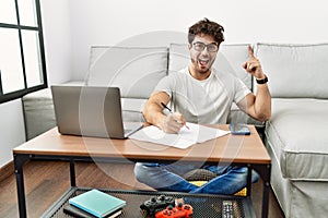 Hispanic man doing papers at home pointing finger up with successful idea