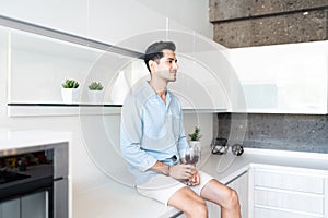 Hispanic Man Drinking Wine In Kitchen