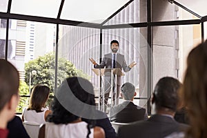 Hispanic man gesturing to audience at business seminar