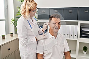 Hispanic man getting medical hearing aid at the doctor looking positive and happy standing and smiling with a confident smile