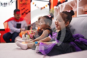 Hispanic man and group of kids having halloween party holding scissors at home