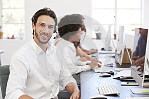 Hispanic man with headset on smiling to camera in an office