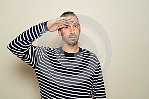 Hispanic man in his 40s saluting the camera with a military salute in an act of honor and patriotism, showing respect