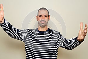 Hispanic man in his forties welcoming on a beige background