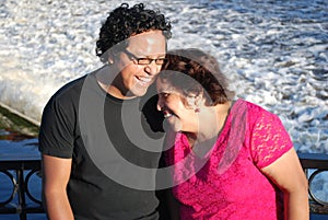 Hispanic man and his mother laughing by a river