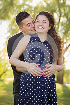 Hispanic Man Hugs His Pregnant Wife Outdoors At the Park