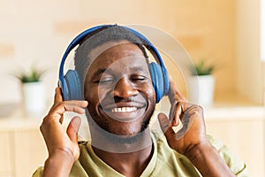 hispanic man listening music in wireless headphones at home