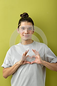 Hispanic man with long hair smiling in love doing heart symbol shape with hands