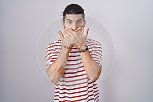 Hispanic man with long hair standing over isolated background shocked covering mouth with hands for mistake