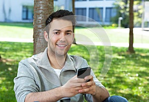 Hispanic man outside in a park sending message