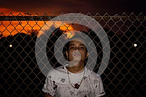 Hispanic man posing on cyclone fence