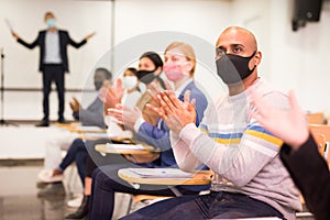 Hispanic man in protective mask applauding during business seminar