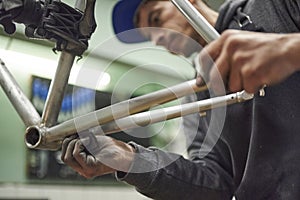 Hispanic man sanding a bicycle frame at his workshop