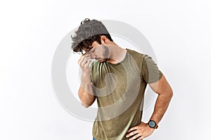 Hispanic man standing over isolated white background tired rubbing nose and eyes feeling fatigue and headache