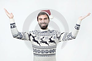Hispanic man in sweater and christmas hat standing raising hands in amazement