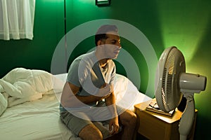 Hispanic man turning on the fan at night