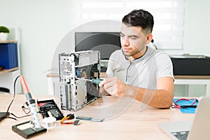 Hispanic man using a screwdriver to fix the pc hardware