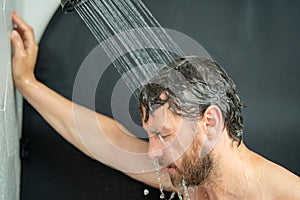 Hispanic man washing hair in bathroom. Guy bathing shower head in bathtub. Male face in shower. Man taking shower in