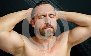 Hispanic man washing hair in bathroom. Guy bathing shower head in bathtub. Male face in shower. Man taking shower in