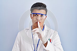 Hispanic man working as scientist asking to be quiet with finger on lips