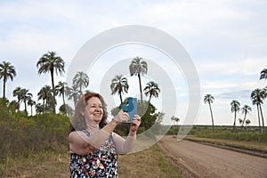 Hispanic mature woman taking a picture in El Palmar National Park, in Argentina