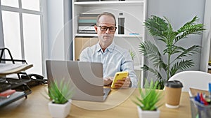 Hispanic middle age man, a serious and successful business worker, sitting at his office table, concentrating on his work, looking