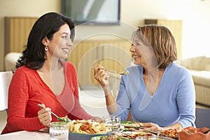 Hispanic Mother With Adult Daughter Enjoying Meal At Home