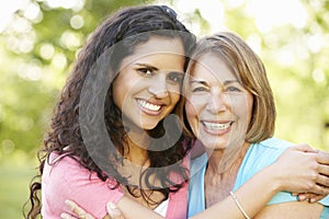 Hispanic Mother And Adult Daughter Relaxing In Park