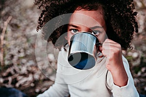 Hispanic mother and afro kid girl doing picnic outdoors relaxing in nature. Autumn season. Family concept