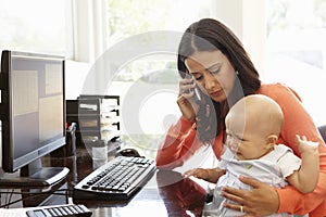 Hispanic mother with baby working in home office