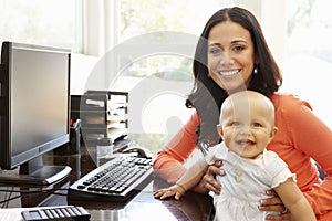 Hispanic mother with baby in working home office