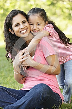 Hispanic Mother And Daughter Relaxing In Park