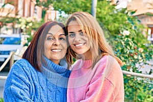 Hispanic mother and daughter smiling happy and hugging at the park