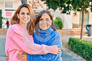 Hispanic mother and daughter smiling happy and hugging at the park