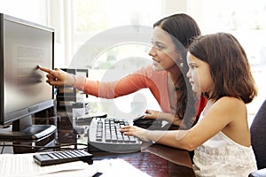 Hispanic mother and daughter using computer at home