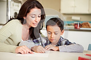 Hispanic Mother Helping Son With Homework At Table