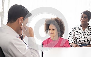 Hispanic physician meeting and diagnosis mixed-race afro children with her African American mother at a hospital. The doctor