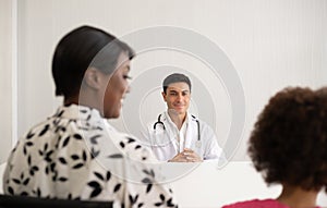 Hispanic physician meeting and diagnosis mixed-race afro children with her African American mother at a hospital.