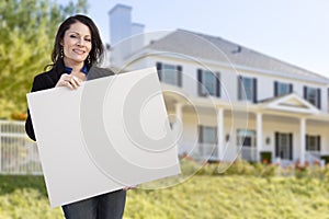 Hispanic Realtor Holding Blank Sign In Front of House