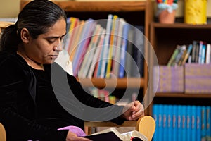 Hispanic Religious Woman Sitting on Rocking Chair and Reading Her Bible