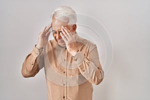 Hispanic senior man wearing glasses with hand on head for pain in head because stress