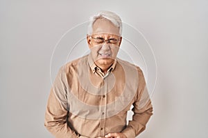 Hispanic senior man wearing glasses with hand on stomach because nausea, painful disease feeling unwell