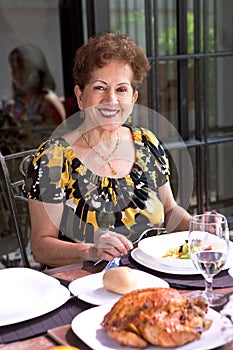 Hispanic senior woman enjoying lunchtime outdoor in a home environment