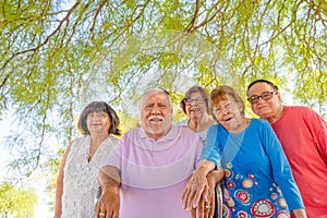 Hispanic Seniors gathered together under a tree