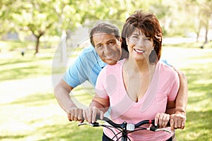 Hispanic senoir couple with bike smiling at camera