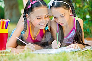 Hispanic sisters drawing in summer park